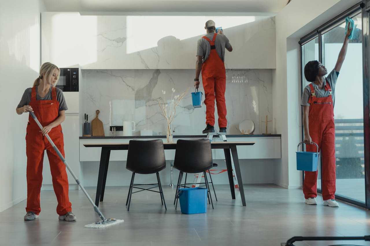 services-04 Group of cleaners in red uniforms mopping and wiping glass in a modern dining room.